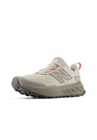 Chaussure de course beige clair avec une tige texturée, des lacets intégrés, des accents orange et une semelle extérieure grise épaisse avec un motif de bande de roulement.