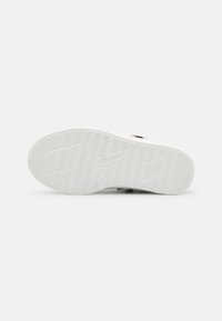 Suela de zapatilla blanca con goma texturizada, con un patrón en forma de cuadrícula y el nombre de la marca "FRIBOO" grabado cerca del talón.