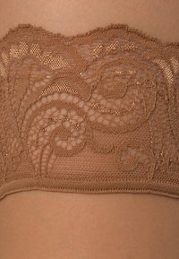 Brown lace lingerie with intricate floral patterns, featuring a soft mesh texture and scalloped edges for a delicate appearance.