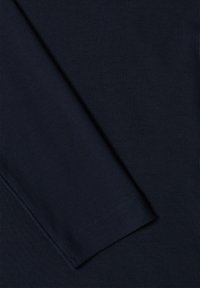 Chemise bleu marine à manches longues côtelée avec une texture lisse et une coupe droite. Dotée d'un ourlet soigné et de manches légèrement fuselées.