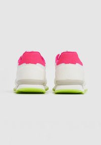Witte sportschoenen met roze suède hielaccenten en groene rubberen zolen. Kenmerken zijn een zachte bovenkant en een gevoerde achterkant voor comfort.