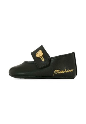 Scarpa in pelle nera con una fascia in velcro e un accento d'oro a forma di orso. Presenta il nome del marchio "Moschino" ricamato in oro. Texture liscia, punta arrotondata.