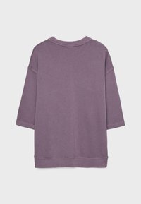 Fioletowy, oversize'owy sweter z opadającymi ramionami i rękawami 3/4, pokazany z tyłu na jednolitym jasnoszarym tle.