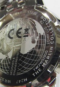 Fond de montre en acier inoxydable avec un motif de globe, marquage "CE" et texte gravé : "Conçu et ingénieré par The Marlin Collection."