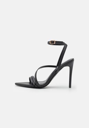 Sandale negre cu toc înalt, cu curea subțire la gleznă și un design elegant. Prezintă trei curele orizontale și un vârf ascuțit. Textură netedă.