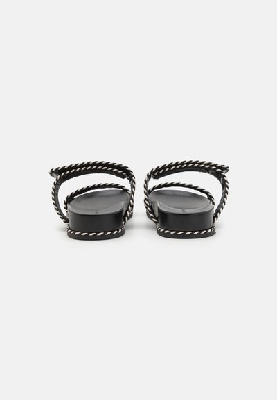 Black flat sandals with rope-style straps, featuring a smooth sole and exposed heel design. Accented with cream-colored rope detailing.