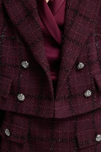 Bordeaux geruite dubbelzijdige blazer met metalen knopen, voorzien van een textuurstof en een subtiele glans, gedragen over een diep bordeaux blouse.