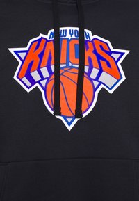 Sweat à capuche noir arborant un logo vif des New York Knicks en orange et bleu, avec un motif de ballon de basket et des cordons noirs.