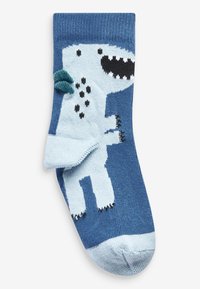 Calcetines azules con un diseño de dinosaurio de dibujos animados en azul claro, con acentos negros y un tejido texturizado; la punta y el puño son de color sólido.