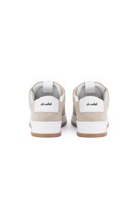 Beige suede sneakers with white accents, round toe, cushioned sole, and branded heel tab. Features a textured rubber outsole.