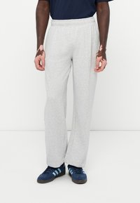 Grå joggebukser med elastisk midjebånd, med en avslappet passform og glatt tekstur. Sammen med blå joggesko med lyseblå striper.