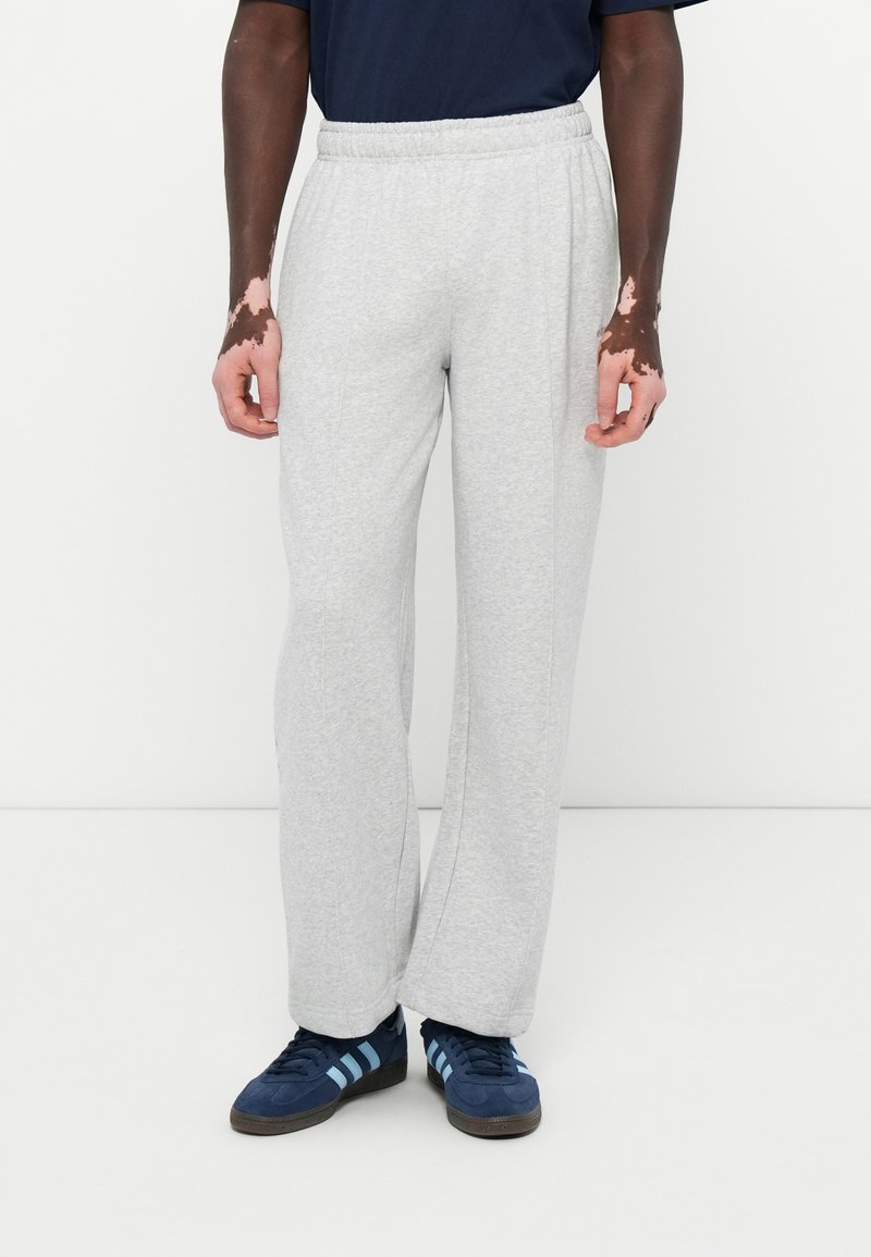 Grå joggebukser med elastisk midjebånd, med en avslappet passform og glatt tekstur. Sammen med blå joggesko med lyseblå striper.