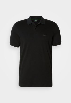 Polo noir en coton, doté d'une patte de boutonnage à deux boutons, de manches courtes et d'un logo discret sur le côté gauche. Texture du tissu lisse.