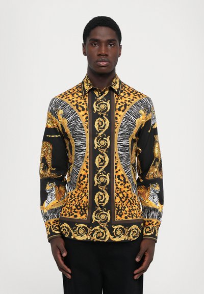 Knap-op skjorte med et dristigt print af tigre og leoparder i guld, sort og orange på en mørk baggrund; klassisk krave og lange ærmer.