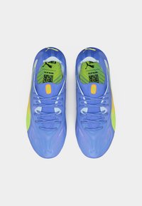 Ζευγάρι μπλε παπούτσια τρεξίματος Puma με κίτρινες και πράσινες λεπτομέρειες, που δείχνουν την άνω όψη με κορδόνια και κωδικούς QR στις εσωτερικές σόλες.