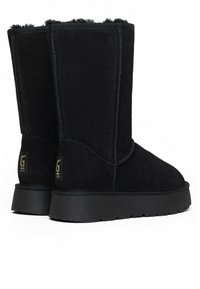 Botas de tobillo de ante negro con un acabado texturizado, parte superior recta y suela plana de goma. Presentan costuras cosidas y logotipos en la parte trasera.