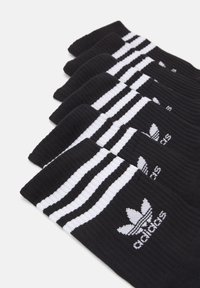 Calcetines deportivos negros con franjas blancas y el logo de Adidas. Fabricados con un material texturizado, tienen un puño acanalado para un mejor ajuste.