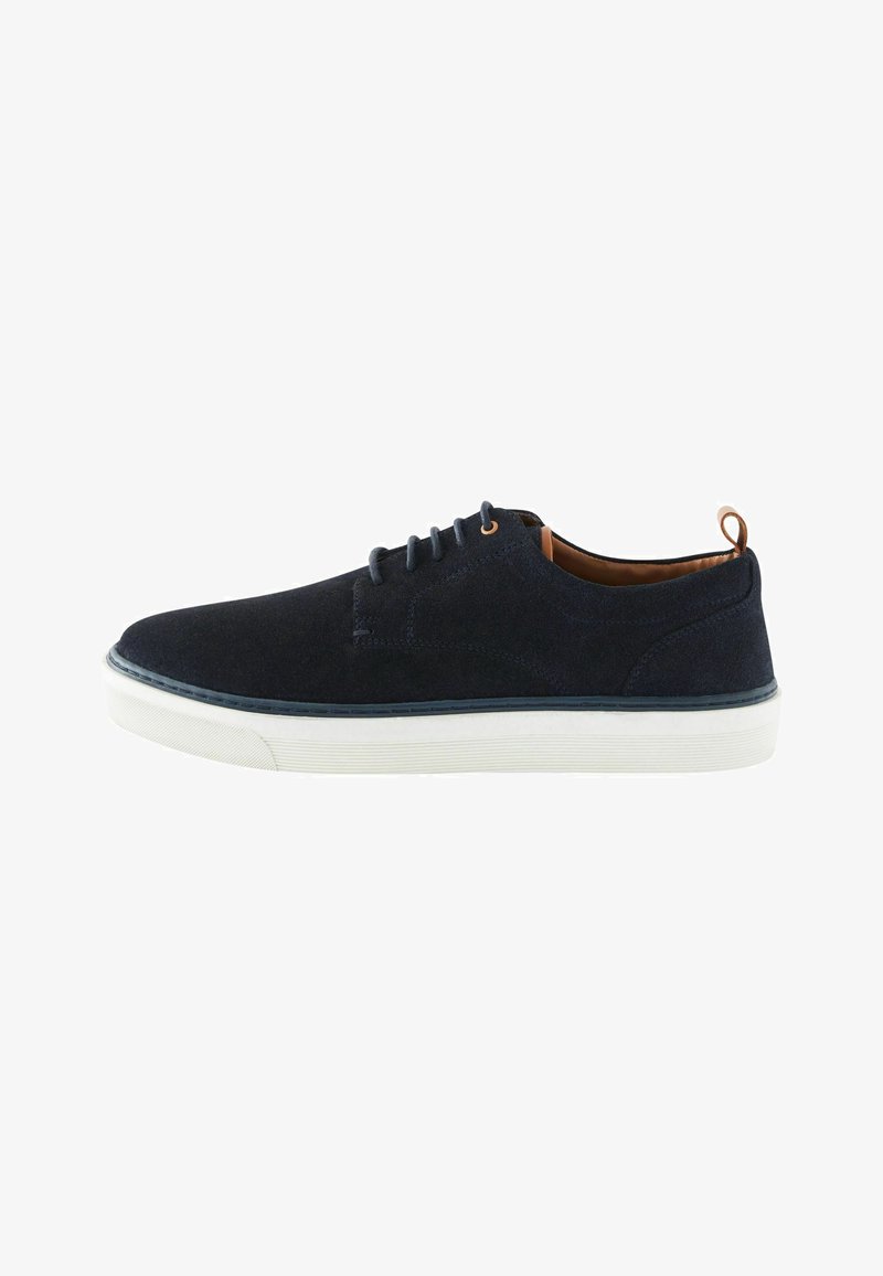 Scarpa stringata in suede blu navy con suola in gomma bianca, dettagli beige e texture sui lati, caratterizzata da punta rotonda e design minimalista.