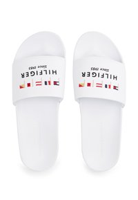 Hvide sliders med flad sål. Stropperne har "Hilfiger" logoet sammen med farverig flagdesign og "siden 1985" tekst.