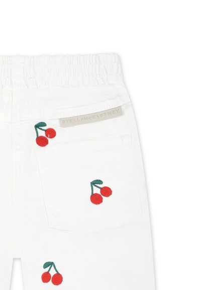 Pantaloni di cotone bianchi con vita elasticizzata, caratterizzati da ricami di ciliegie rosse sulla tasca anteriore e un'etichetta del marchio sul retro.