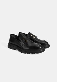 Schwarze Lederloafers mit einer runden Spitze, klobiger Gummisohle und goldenen Akzenten. Glatte Textur mit einem klassischen Design.