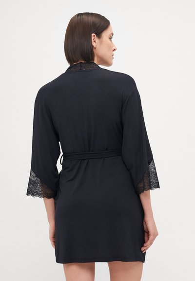 Black robe made from soft fabric, featuring lace accents on bell sleeves and collar. Ties at the waist for a fitted silhouette.