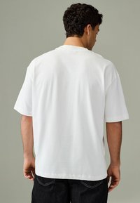 Hvid kortærmet T-shirt lavet af bomuld, med rund halsudskæring og en afslappet pasform, med en glat tekstur og ingen synlige mønstre.