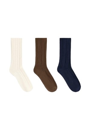 Tre calzini a coste bianchi, marroni e blu navy, disposti affiancati su uno sfondo bianco.