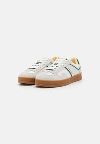 Zapatillas blancas con acentos verdes, parte superior de ante y sintético, suela de goma, diseño de cordones y cuello acolchado.