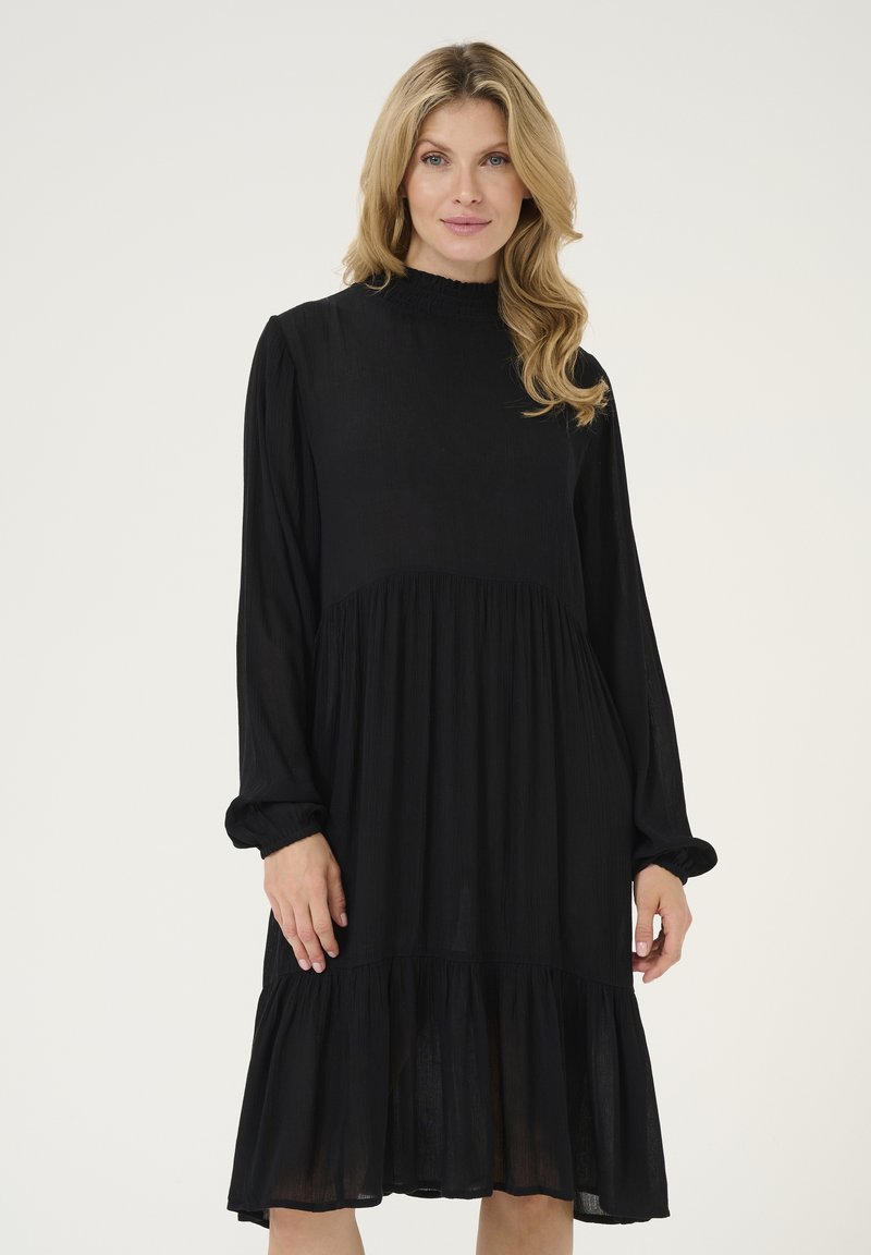 Black dress with long sleeves, high neckline, and a tiered skirt. Made of lightweight, textured fabric, featuring a flowing silhouette.