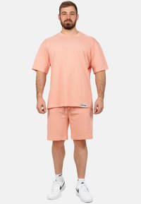 T-shirt surdimensionné couleur pêche avec short assorti, en coton doux, présentant des accents de logo et une ceinture à cordon.