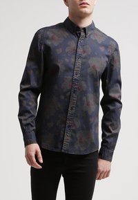 Camicia a maniche lunghe con colletto in tessuto blu scuro con motivo floreale rosso e verde, bottoni frontali e design aderente.