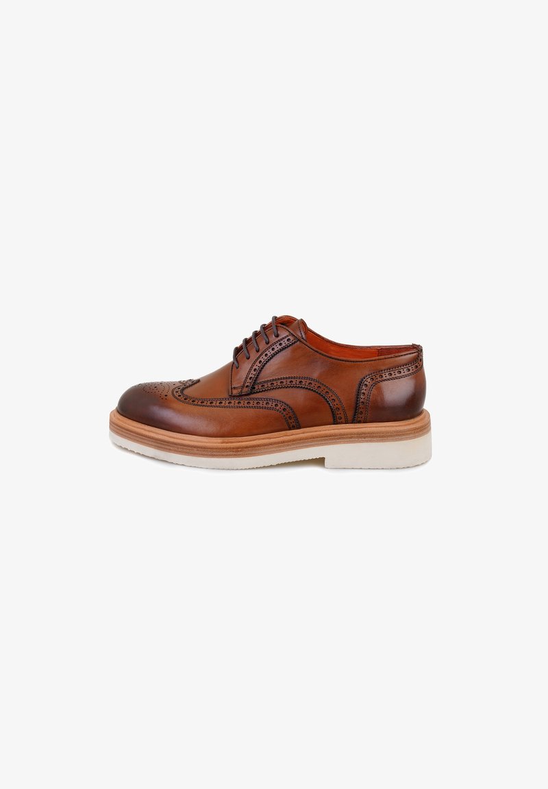 Chaussure à lacets en cuir marron avec des détails brogue, bouts lisses, et une semelle texturée blanche contrastante. Design classique avec des accents élaborés.