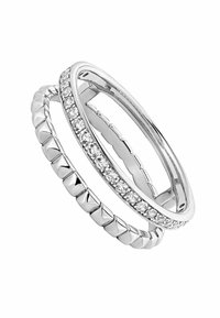 Tres anillos de plata apilados: uno con una superficie lisa, uno con texturas alternadas entre lisa y con puntas, y uno adornado con piedras preciosas transparentes.