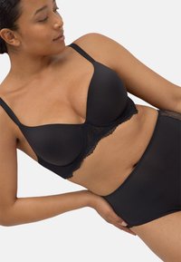 Sujetador negro con borde de encaje, fabricado en un tejido suave, con soporte de aros y tirantes ajustables, combinado con bragas negras de cintura alta con un borde sin costuras.