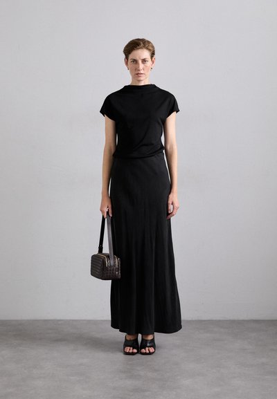Black short-sleeve top paired with a long black skirt, black open-toe sandals, and a small woven black handbag. Simple and minimalistic design.