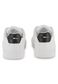 Λευκά δερμάτινα sneakers με λεία υφή, μαύρη ενισχυμένη φτέρνα με δύο χρυσές λεπτομέρειες και επίπεδη λαστιχένια σόλα. Απλός και κλασικός σχεδιασμός.