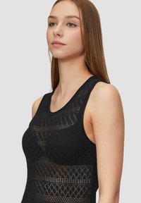 Schwarzes ärmelloses Top mit einem strukturierten Muster aus offenen Rautenformen, runden Ausschnitt und taillierter Silhouette.