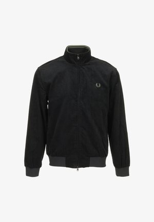 Schwarze Cordjacke mit Stehkragen, Reißverschluss und gerippten Bündchen. Mit kleinem, besticktem Logo auf der linken Brust.