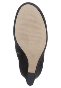 Suela de zapato de ante negro con textura estriada, forma redondeada y tacón afilado. Talla 37 marcada en la base. Suela beige lisa.