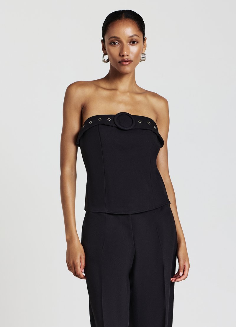 Schwarzes trägerloses Oberteil mit figurbetontem Oberteil, rundem Akzent in der Mitte und dekorativen Ösen entlang des Halsausschnitts. Glatte Textur.