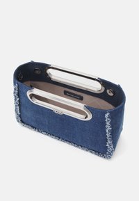 Denim handbag with silver hardware, frayed edges, and an open design. Interior features a logo label and smooth fabric lining.