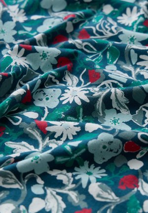 Katoenen stof in diep teal met een bloemmotief met lichtblauwe, rode en groene tinten. Gladde textuur met zachte plooien en plooien.