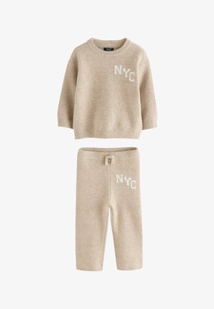 Bežani pleteni komplet džemper i hlače s natpisom "NYC" u bijeloj boji na prsima i gornjem dijelu bedra, s rebrastim manžetama i pojasom na vezanje.