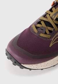 Purple athletic shoe with mesh upper, reinforced toe cap, yellow laces, and textured sole featuring black traction studs and a speckled midsole.