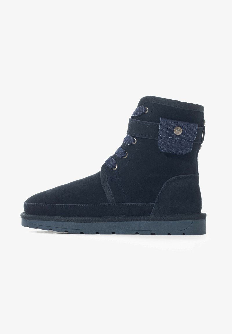 Botas de tobillo de color azul marino hechas de ante, con un diseño de cordones, un bolsillo lateral con solapa de mezclilla y una suela de goma resistente.