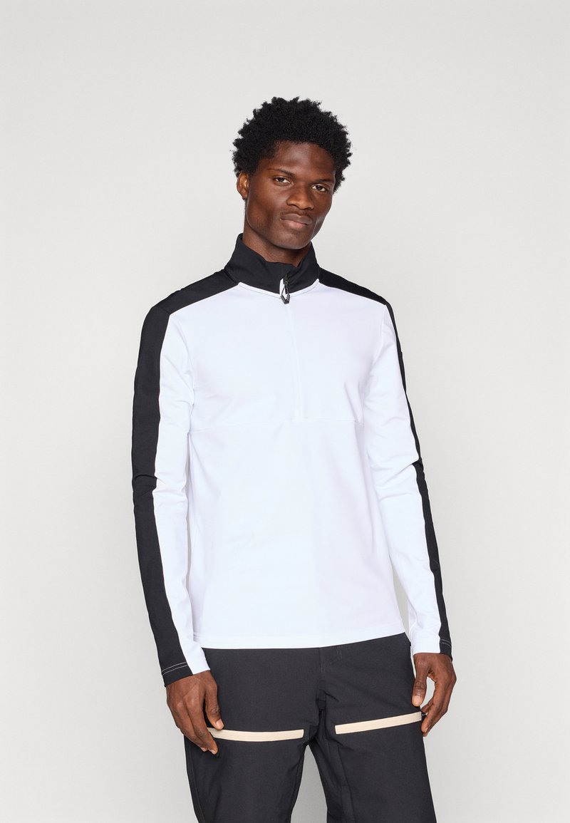 Valge tõmblukuga pikka varrukatopper, millel on mustad aktsendid õlgadel ja varrukatel, valmistatud siledast ja kergest kangast.