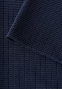 Tessuto navy con una texture a righe. La superficie presenta linee verticali e un aspetto morbido e lavorato. I bordi sono rifiniti in modo pulito.