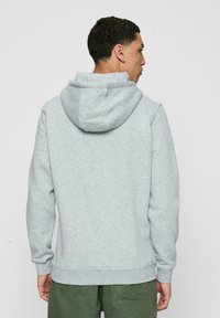 Grå hettegenser med justerbar snor i hetten, ribbestrikkede mansjetter og nederkant. Laget av mykt stoff, har en avslappet passform og minimale sømdetaljer.