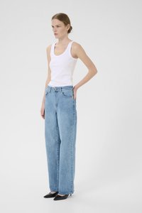 Lyseblå vide jeans i denim med klassisk fem-lomme-design og knappelukking, kombinert med en hvit tanktopp.